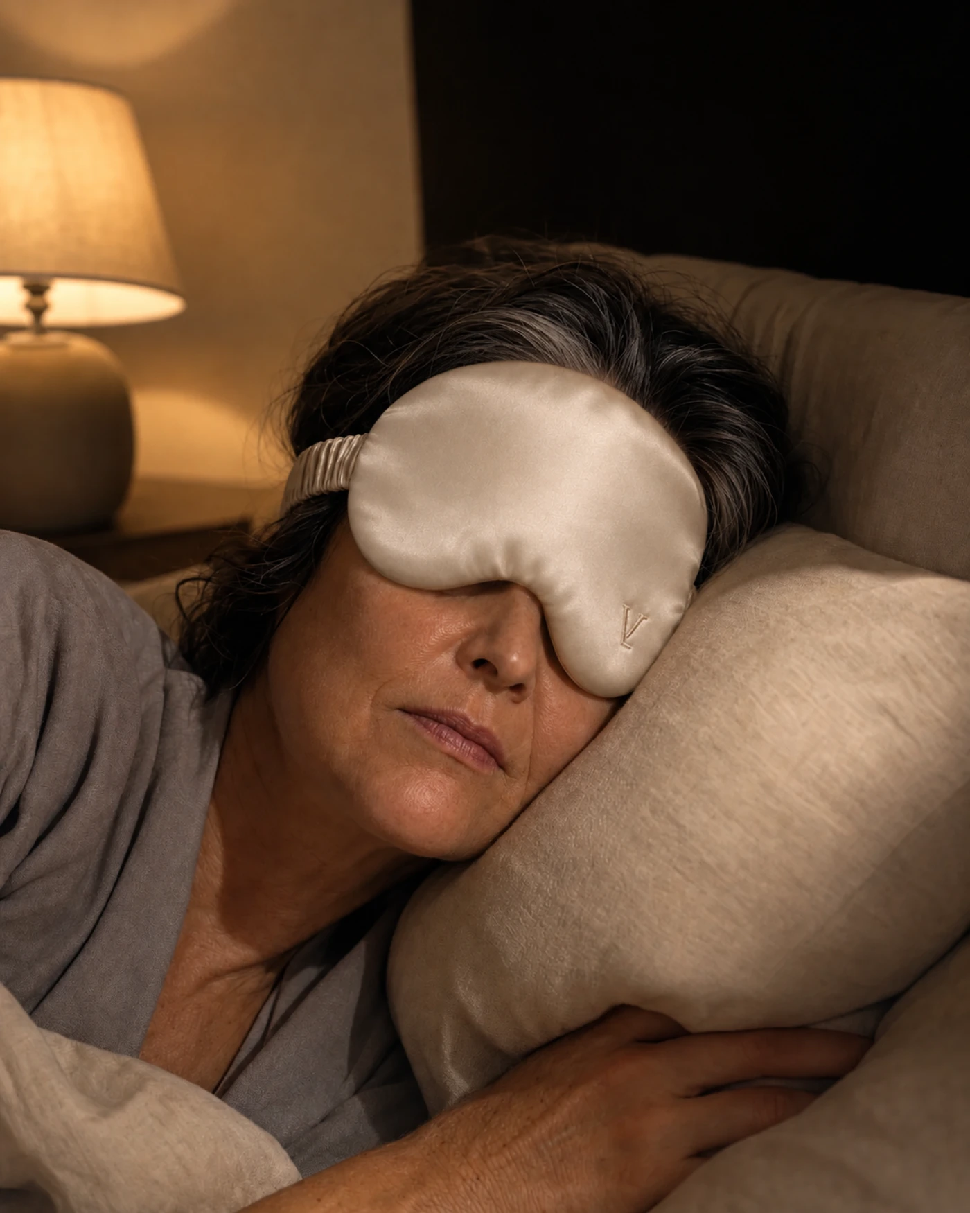 Una mujer durmiendo con VEIL mientras la lámpara del otro lado de la cama sigue prendida